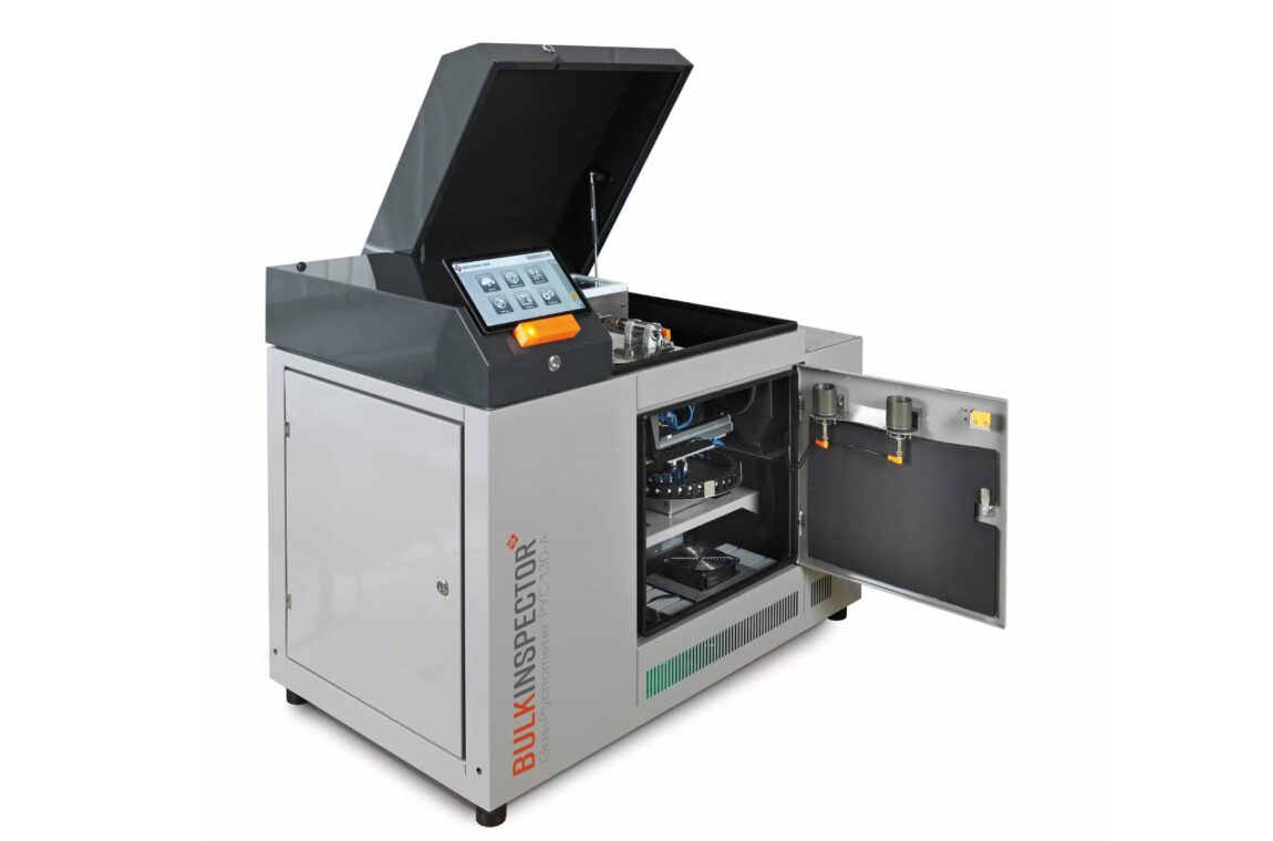 The SIEBTECHNIK TEMA BULKINSPECTOR PYC 130A gas pycnometer seen from the front, the front and top covers are open. The tablet with the open app for operation, as well as the tablet shelf with the indicator light for operational readiness and the USB charging port.